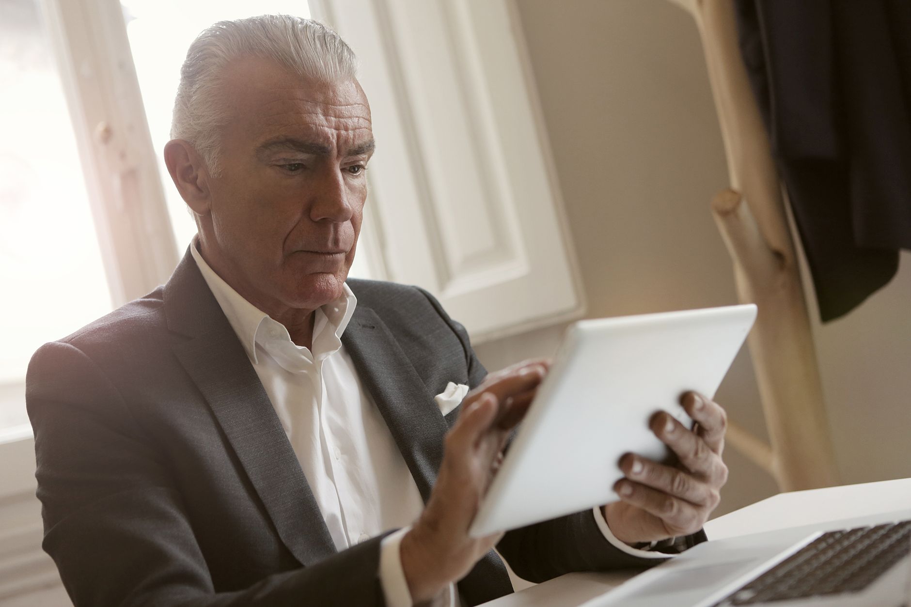 Senhor de terno usando um tablet em ambiente elegante