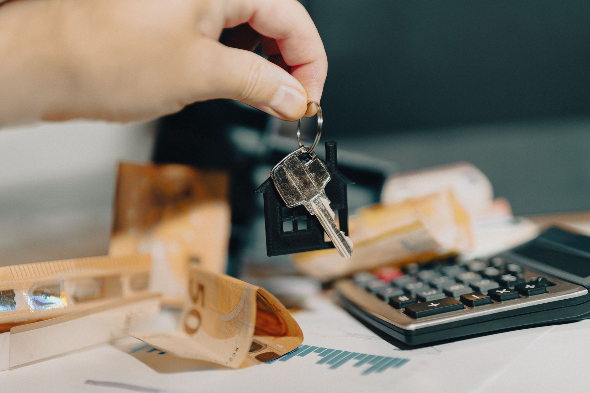 Mão segurando chaves de carro ao lado de uma calculadora